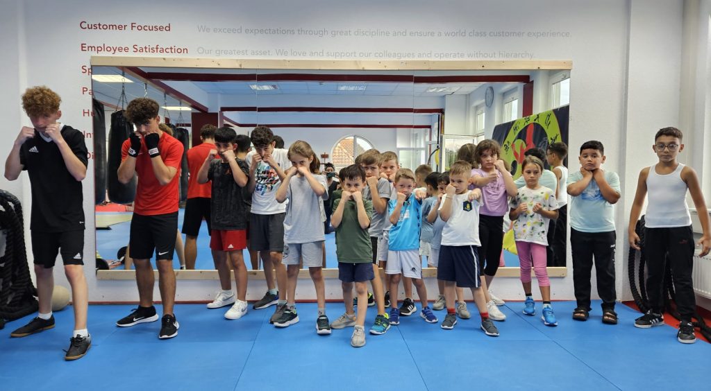 Kindergruppe in Boxhaltung auf der blauen Trainingsmatte im Fight & Fitness Studio Heilbronn