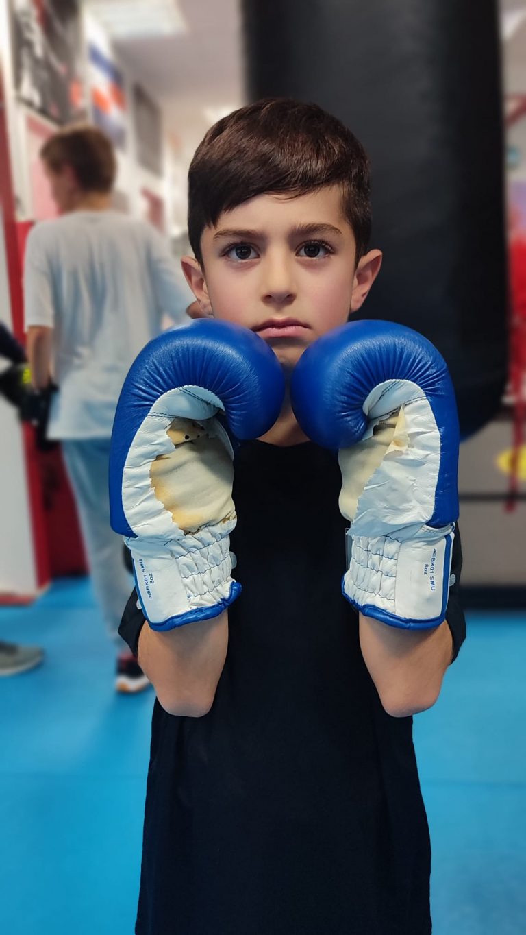 Junge mit blauen Boxhandschuhen im Studio